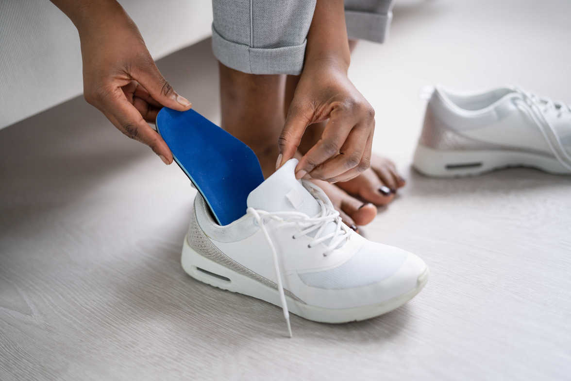 A person putting custom made orthotics in his shoes to alleviate foot pain