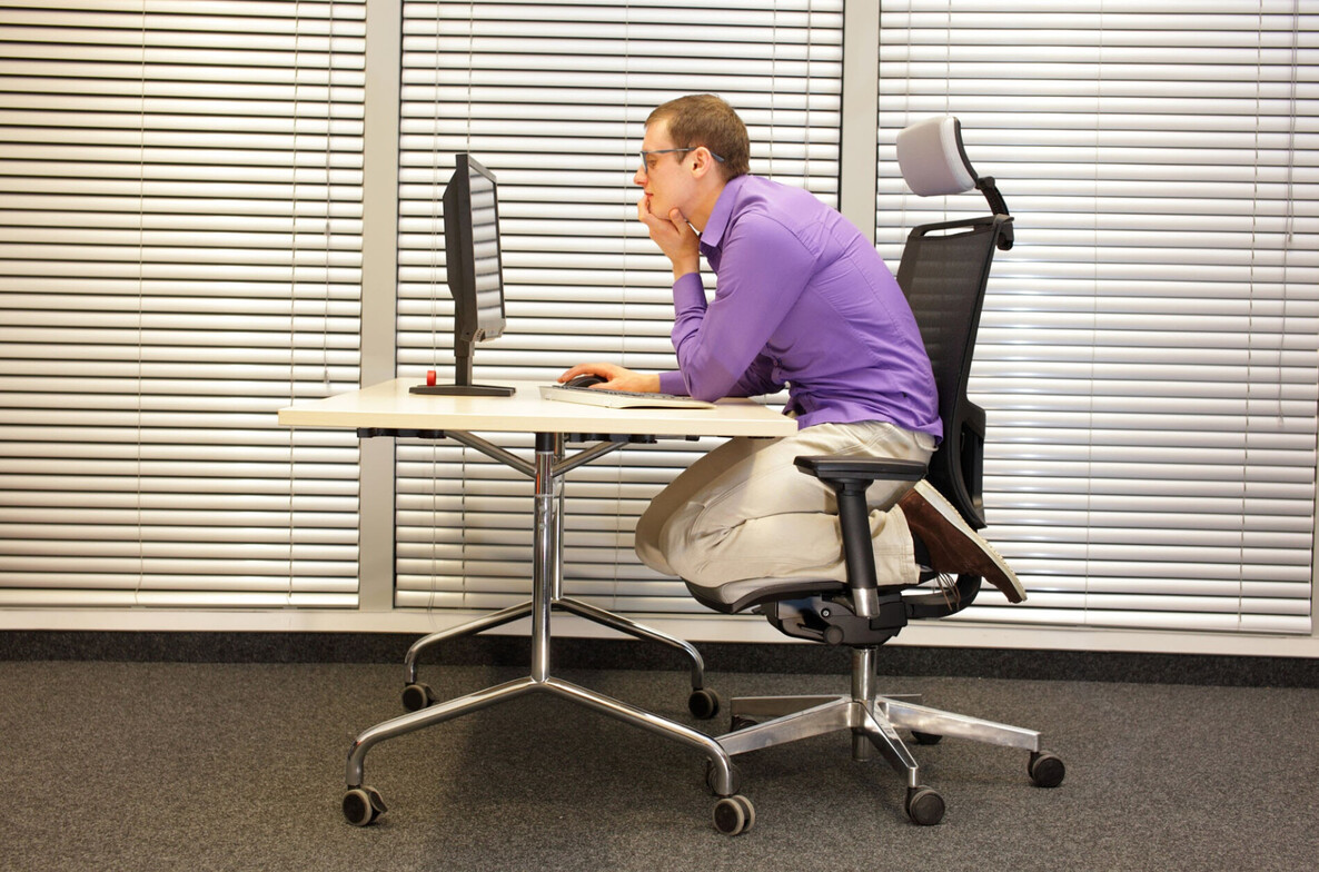Office desk worker slouching with forward head posture causing neck and upper back pain